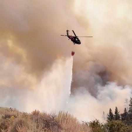 ２３日、米西部ネバダ州リノで山火事の消火活動をするヘリコプター（ネバダ州軍提供、ロイター＝共同）