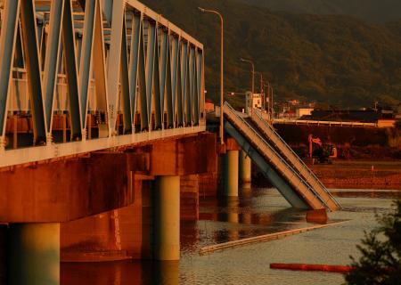 夕日に染まった、崩落したままとなっている球磨川に架かる橋＝２７日夕、熊本県八代市