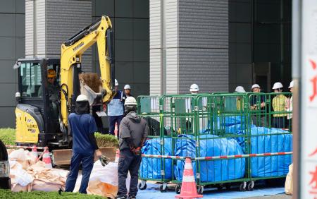さいたま新都心合同庁舎1号館で、花壇に除染土を運ぶ作業員ら=30日午前、さいたま市
