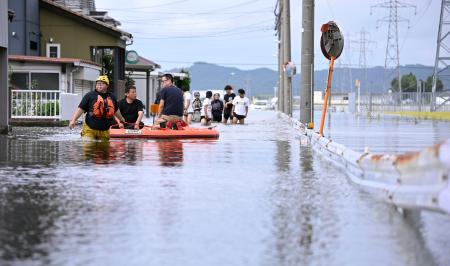 大雨で冠水した福井県坂井市内の道路。住民らがボートに乗り、必要物資の買い出しに向かっていた=30日午後2時44分
