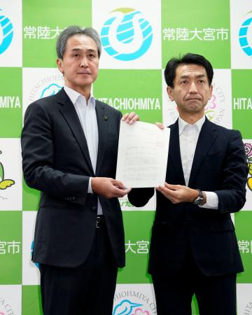 原発の運転に伴う高レベル放射性廃棄物の最終処分場選定を巡り、経産省の担当者(右)から文献調査実施の申し入れ文書を受け取った茨城県常陸大宮市の鈴木定幸市長=31日午後、常陸大宮市役所