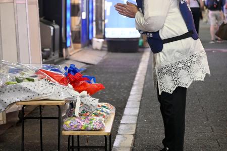 東京・新宿の歌舞伎町で、ビル跡地に献花し手を合わせる植田安子さん＝８月３１日午後１０時ごろ
