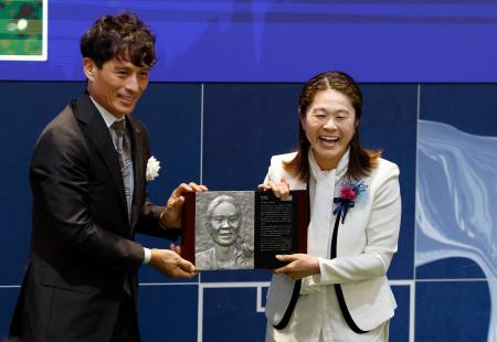 日本サッカー殿堂の掲額式典で、レリーフを手に笑顔を見せる澤穂希さん。左は宮本恒靖会長＝１日、東京都内