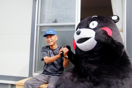 　熊本県氷川町に完成した仮設住宅で「くまモン」と写真に納まる入居者の宮川高弘さん＝５日午前