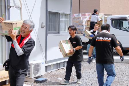 入居が始まった仮設住宅に支援物資を運び込む有志のトラック運転手ら=5日午前、熊本県氷川町