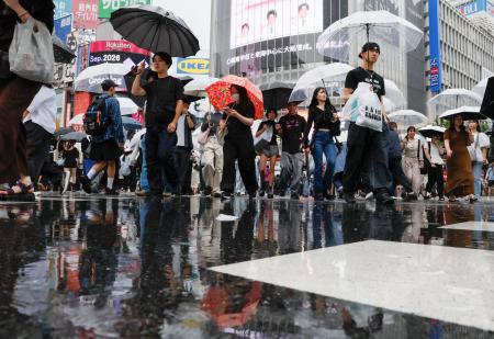 雨が降る中、東京・渋谷のスクランブル交差点を行き交う人たち＝６日午後