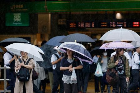 雨の中、信号を待つ人たち=7日午前、JR新宿駅前
