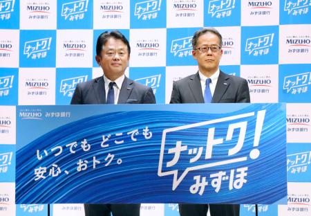 記者会見でボードを手にする、みずほ銀行の加藤勝彦頭取（左）＝７日午前、東京都千代田区