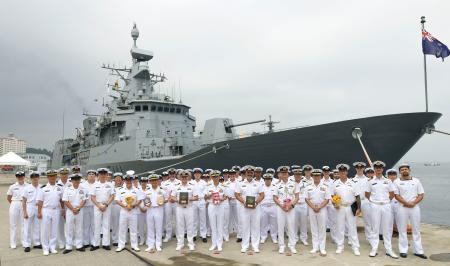 寄港したニュージーランド海軍の哨戒艦テ・マナと写真に納まる同国海軍と海上自衛隊の関係者＝８日午前、海上自衛隊横須賀基地