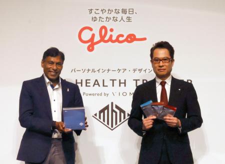 記者会見で写真に納まる江崎グリコの江崎悦朗社長(右)ら=9日午後、東京都内