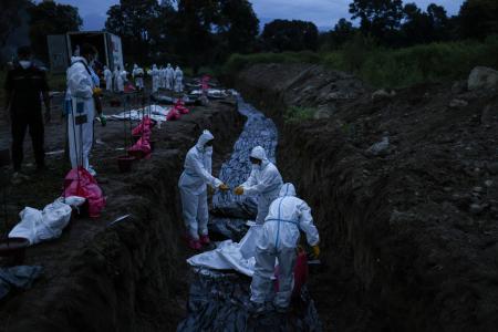 １０日、洪水と土石流による犠牲者の集団埋葬が行われる中、穴を掘る治安要員＝ネパール・ビドゥール（ロイター＝共同）