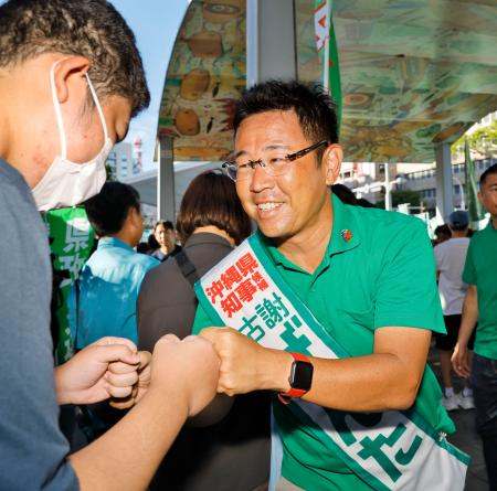 街頭演説に集まった人とタッチを交わす古謝玄太氏=12日午後、那覇市