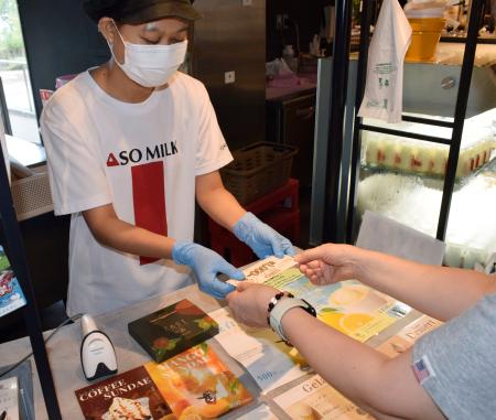 観光支援のクーポンを受け取る阿部牧場の直営販売店の従業員=12日、熊本県阿蘇市