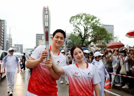愛知・名古屋アジア大会の聖火リレーでランナーを務め、２人でトーチを掲げるミラノ・コルティナ冬季五輪金メダルの三浦璃来さん（右）と木原龍一さん＝１６日午後、名古屋市瑞穂区（代表撮影）