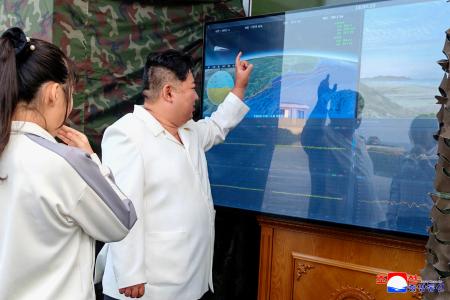 北朝鮮のミサイル総局が実施した新型兵器の試験をモニターで確認する金正恩朝鮮労働党総書記（右）と娘＝２０日（朝鮮中央通信＝共同）