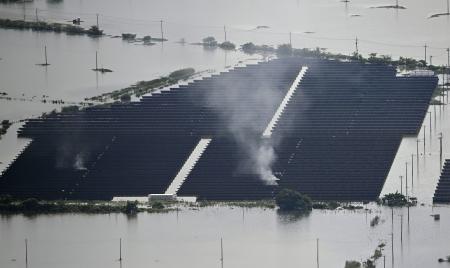 堤防が決壊し冠水した千葉県・印旛沼の近くの太陽光発電施設から上がる煙＝２４日午前１１時、成田市（共同通信社ヘリから）