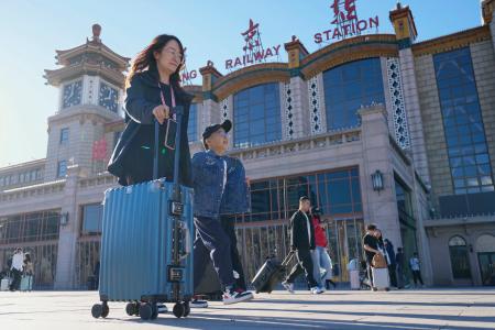 国慶節を迎え、北京駅前の広場をトランクを引いて歩く人たち＝１日（共同）