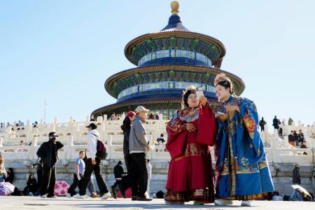 北京の天壇公園で漢族の伝統衣装「漢服」を着て写真を撮る女性たち=1日(共同)