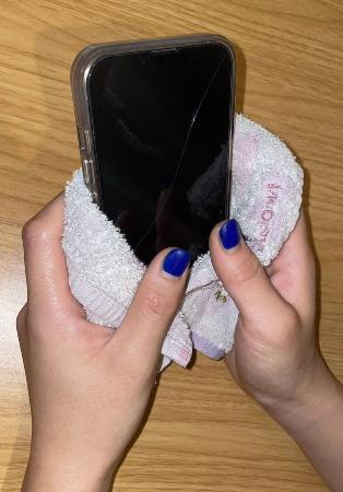手汗でスマートフォンが反応しづらくなるため、ハンドタオルを巻くようにして使う女性＝９月、東京都内