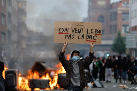 抗議デモ中に「警察は要らない」とプラカードを掲げる生徒＝１日、フランス北部リール（ＡＰ＝共同）