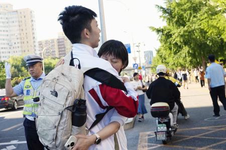 中国の全国一斉大学入試「高考」の会場前で保護者と抱き合う学生＝６月、北京（共同）