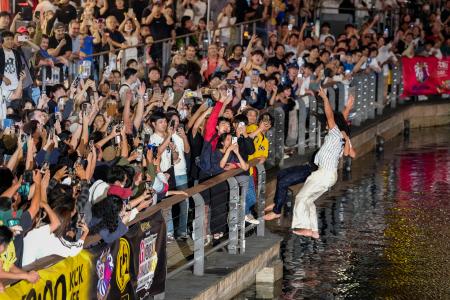 阪神タイガースがセ・リーグ連覇を決め、大阪・ミナミの道頓堀川に飛び込む人たち=3日夜