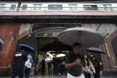 傘を差して東京・新橋駅前を歩く人たち＝９月３０日