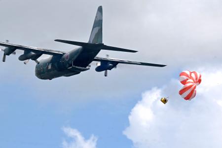 ６日、フィリピン中部タクロバンで、救援物資に見立てた箱を投下する航空自衛隊の輸送機（共同）