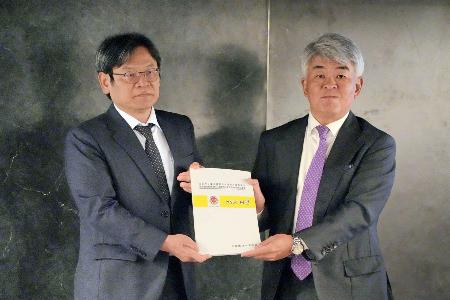 台湾の国家発展委員会の葉俊顕主任委員（左）に「白書」を手渡す台北市日本工商会の増田裕一理事長＝７日、台北市（共同）