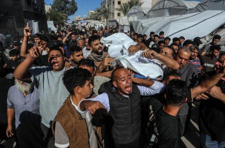 イスラエル軍の攻撃で死亡した16歳の少年の遺体を運ぶ人たち=7日、パレスチナ自治区ガザ南部ハンユニス(ゲッティ=共同)