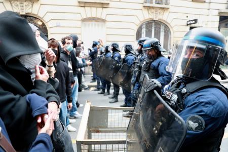 7日、パリ政治学院の前で向かい合うデモ隊と警官隊(共同)
