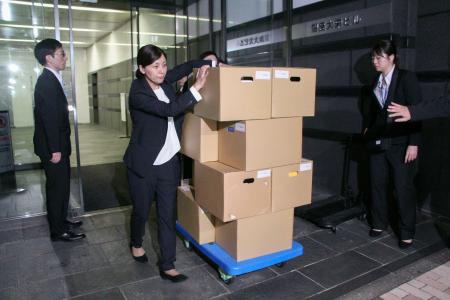 ビール大手の価格カルテル疑惑で、関係先として業界団体「ビール酒造組合」を捜索し、段ボールを運び出す公正取引委員会の担当者ら=8日未明、東京都中央区