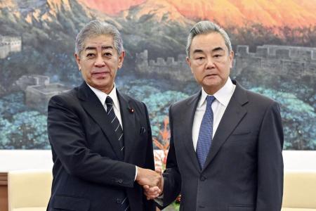 中国の王毅外相（右）と握手する岩屋毅前外相＝９月、北京（新華社＝共同）
