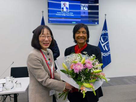 国際刑事裁判所(ICC)を訪問し、赤根智子所長(左)から花束を贈られるピレイ元国連人権高等弁務官=12日、オランダ西部ハーグ(ICC提供・共同)
