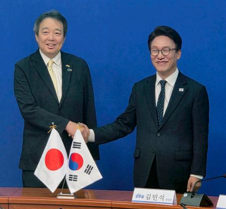 水嶋光一駐韓国大使（左）と握手する韓国の革新系与党「共に民主党」の金民錫代表＝１５日、ソウル（共同）