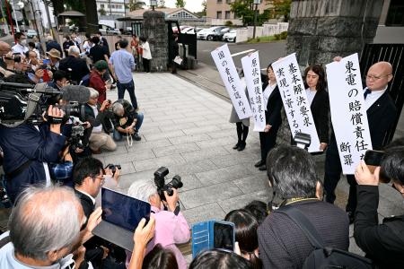 東電福島第１原発事故を巡る福島県浪江町津島地区住民の集団訴訟の控訴審判決後、紙を掲げる原告側弁護士ら＝１６日午後、仙台高裁前