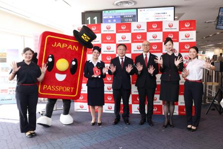 日本航空と外務省が開いた記念イベントで「パスポくん」と写真に納まる関係者ら＝１７日午後、羽田空港