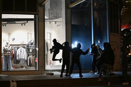 店舗のショーウィンドウを破壊する暴徒＝１８日、パリ（ＡＰ＝共同）