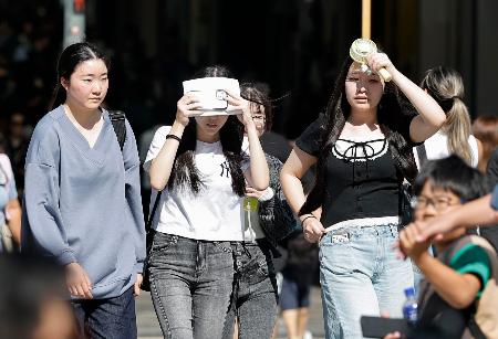 強い日差しの下、大阪・道頓堀を歩く人たち＝２１日午前