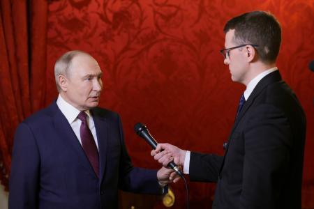２２日、モスクワでロシア国営テレビ記者の質問に答えるプーチン大統領（左）（ロシア大統領府提供・タス＝共同）